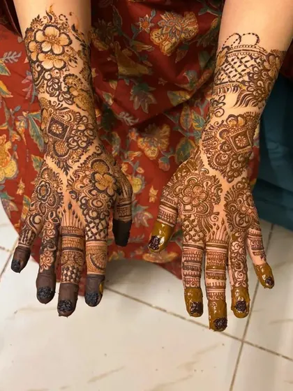 Another intricate non bridal design with a mix of floral and geometric patterns. The dark tips on the fingers add a traditional touch.