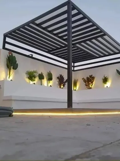 A minimalist raised platform under a pergola, with the floor and surrounding area finished in concrete. The design is accented by a single line of LED lighting at the base.