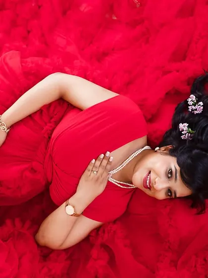 A lovely top-down portrait on a bed of red fabric, with small flowers scattered in the hair for a delicate, feminine touch.