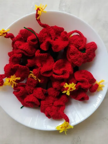 A bowl of my crochet hibiscus (jaswand) flowers. The bright red color and yellow stamen detail make them a beautiful addition to any pooja or festive setup.