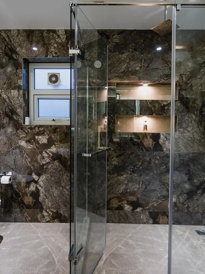 The shower area in this bathroom is a statement in itself, with dramatic dark brown marble tiles and a built-in niche for toiletries.