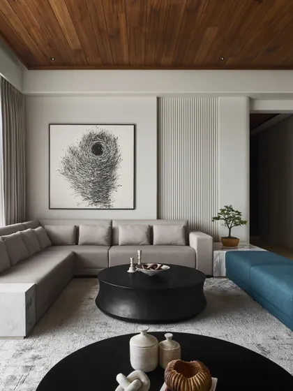 The living room features a stunning wood ceiling with concealed lighting, embodying quiet luxury. A custom-designed double coffee table in black concrete anchors the space, while a teal bench adds a vibrant yet sophisticated accent.