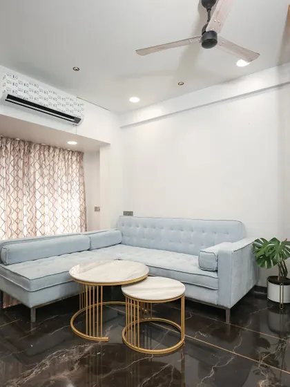 A custom powder-blue L-shaped sofa provides ample seating, while the nested coffee tables add flexibility and a modern touch.
