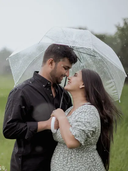 A close-up, intimate shot of a couple huddled together under an umbrella in the rain.