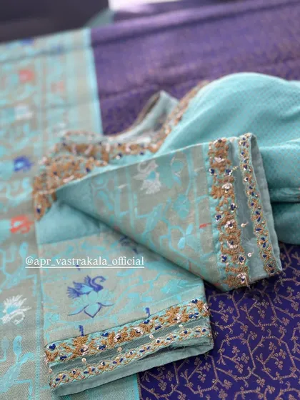 A light blue blouse with delicate gold embroidery on the cuffs.