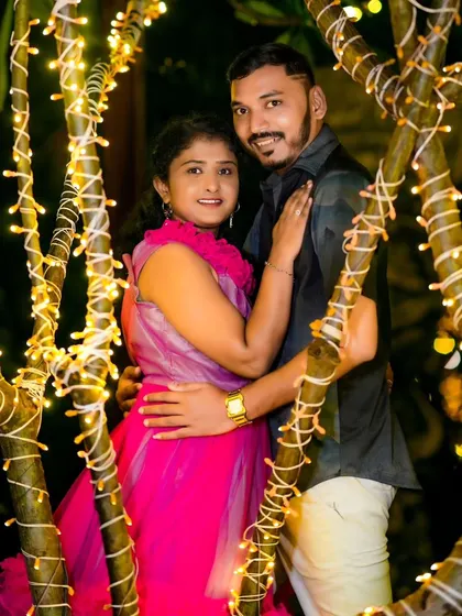 An intimate pre-wedding photo taken through branches wrapped in fairy lights, creating a beautiful and dreamy frame around the couple.