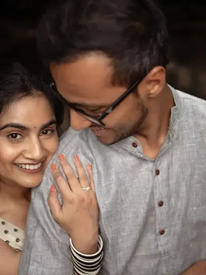 A cozy and intimate pre-wedding portrait. The groom's embrace from behind and the bride's happy smile make for a genuinely warm and loving photograph.
