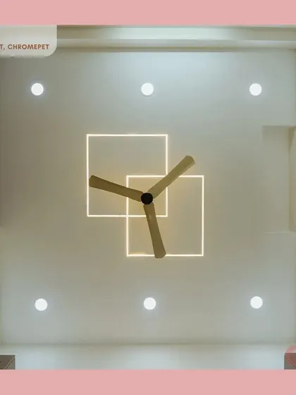 A creative false ceiling design in a bedroom, featuring overlapping backlit squares that add a modern, geometric touch around the fan.