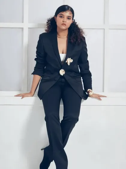 A full-length shot displaying a powerful and chic look with a tailored black suit. The makeup is polished and clean, with defined features that photograph beautifully for commercial and corporate lifestyle shoots.