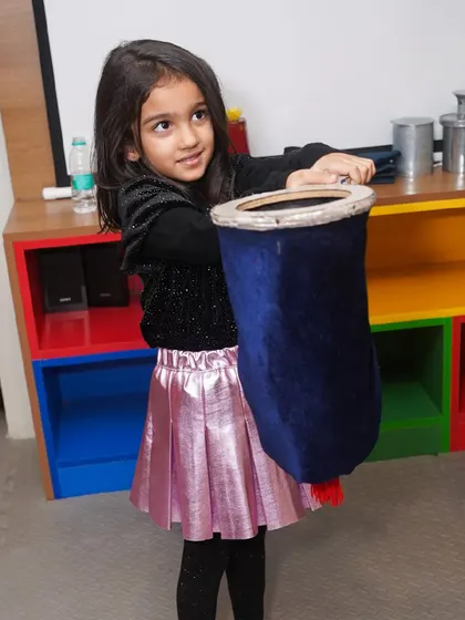 A young girl gets to be the magician's assistant, holding a prop and feeling like part of the magic.
