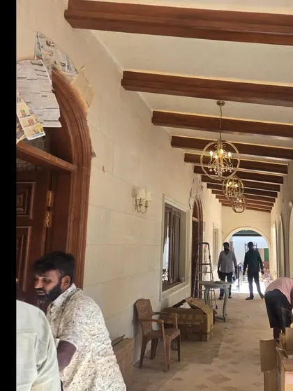 A corridor in the Veerabhavana Villa nearing completion. The exposed wooden ceiling beams and arched doorways are in place, with protective paper still covering some elements as final touches are made.