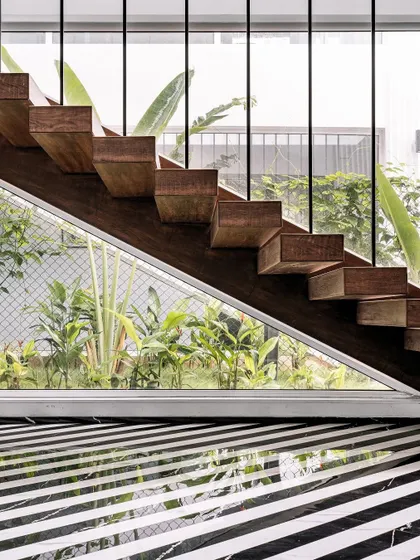 Detail is the language of luxury. This floating staircase at the Tellado home is a testament to that belief. I designed it with solid wood treads and sleek supports to create a sense of lightness, framing the lush greenery outside and complementing the bold, striped marble flooring.