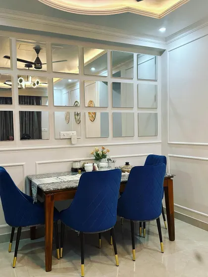 In this Jasola dining space, I used a wall of mirrors to make the area feel larger and brighter. The royal blue velvet chairs add a pop of color and a touch of luxury.
