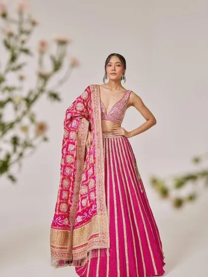 A beautiful fuchsia lehenga with a striped skirt and a traditional bandhani dupatta. This look is a perfect blend of modern design and heritage craft, ideal for a contemporary bride.