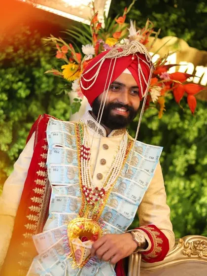 A happy groom during his wedding ceremony, framed by colorful flowers and a blurred foreground.