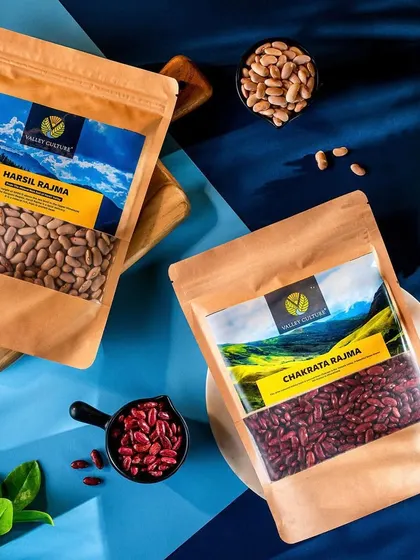 A colorful flat lay of Valley Culture's Harsil and Chakrata Rajma packets. The contrast between the blue background and the earthy tones of the packaging creates a visually striking image for these regional staples.