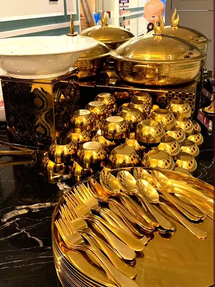 A close-up of our gleaming gold-plated cutlery and serveware. We believe that luxury is in the details, and we provide the finest equipment to ensure your event is stunning from every angle.