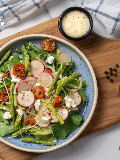 A beautiful and healthy salad featuring asparagus, radish, cherry tomatoes, and feta cheese. It's a perfect side dish or a light main course for a health-conscious crowd.