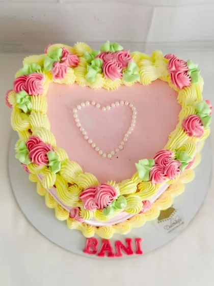 A lovely heart-shaped cake with vintage-style piping in pastel yellow and pink.