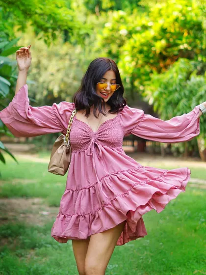A joyful, carefree shot of a model twirling in a pink summer dress. This captures a feeling of movement and happiness, perfect for a lifestyle brand.