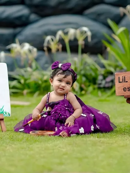 A little princess artist! This girl is wearing a beautiful purple dress for her 'Lil Picasso' themed shoot in the garden.
