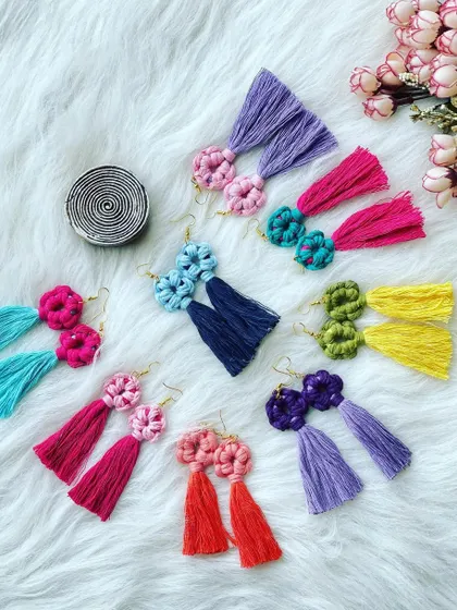 A beautiful flat lay of my flower-knot tassel earrings. Each pair features a detailed floral knot at the top with a flowing tassel below, shown here in several bright, two-tone color combinations like pink and teal, or yellow and green.