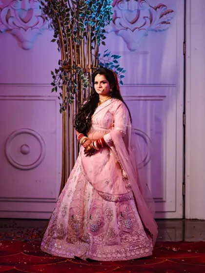 A full-length shot of the bride, showcasing her beautiful pink lehenga and the intricate details of her outfit. Her confident pose makes for a wonderful solo portrait.