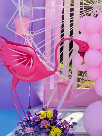 A close-up of the pink flamingo prop next to a Ferris wheel and a cascade of pink balloons.