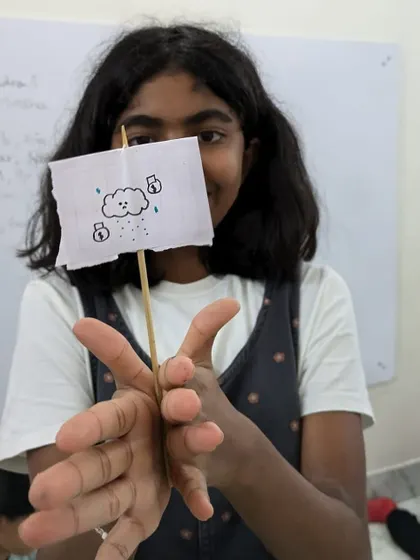 A child proudly displays her "bird in a cage" illusion, a simple yet amazing experiment demonstrating the scientific concept of persistence of vision.