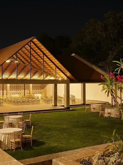 The main event hall at Samavana glows at night, its open structure revealing the celebration within. The design provides a beautiful backdrop for events, blending architectural form with the surrounding garden.