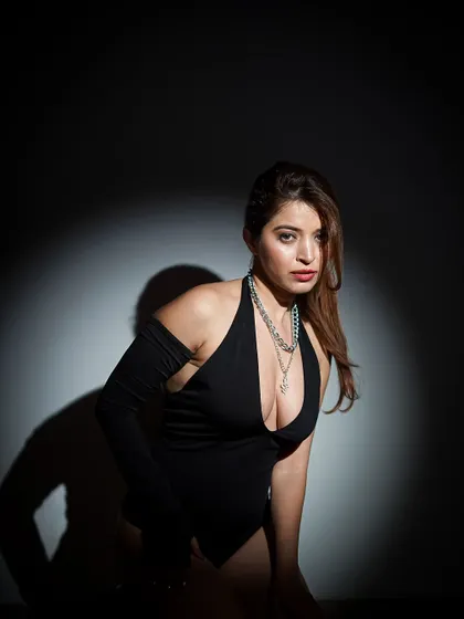 A powerful and confident pose, with the spotlight creating a strong shadow and a sense of drama.