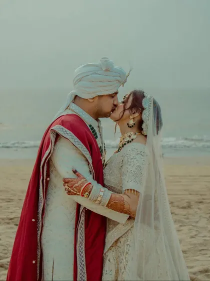 A romantic kiss on the beach. This classic destination wedding portrait captures the love and happiness of the couple against the serene ocean.