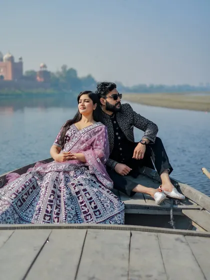 Another perspective from the Yamuna, this shot captures the couple in their ornate outfits, looking like royalty as they float by the Taj Mahal.