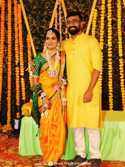 A beautiful portrait of a Haldi bride and groom. Her jewellery, made with delicate pink flowers and mogra buds, perfectly complements her traditional orange and green saree.