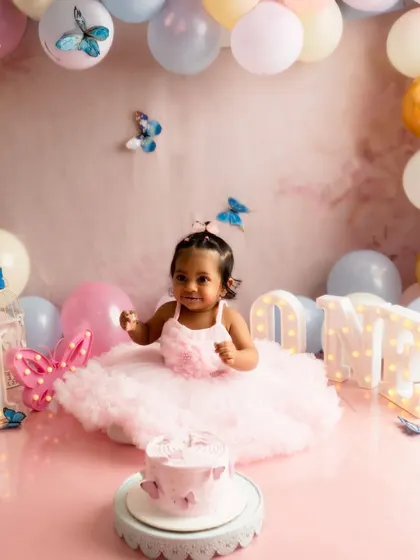 A wider view of a complete cake smash setup. This butterfly theme includes a custom backdrop, a balloon arch in pastel colors, and light up letters spelling 'ONE' to create a dreamy, celebratory atmosphere.