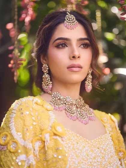 A portrait of our bride Bhumika, showcasing her elegant jewelry and the soft, romantic makeup we designed for her Haldi.