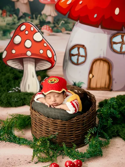 A whimsical mushroom-themed newborn session. The baby, wearing a cute gnome-like hat, sleeps in a basket in an enchanted forest setting.