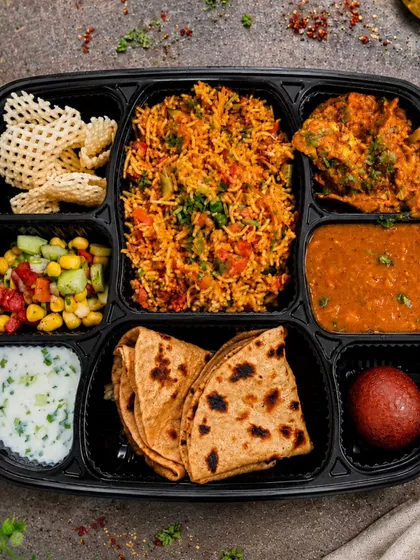 Veg pulav, chole, folded bread, raita and gulab jamun appear in this display of our vegetarian compartment meal tray.