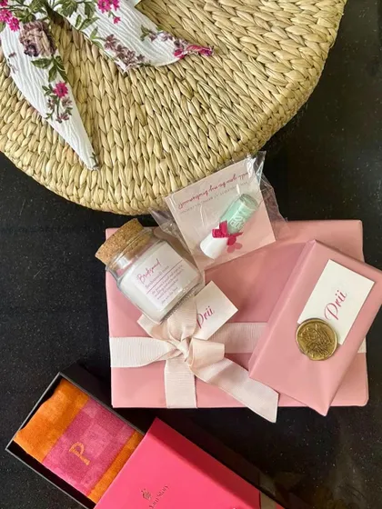 A detailed look at the contents of a bridesmaid gift, including a personalized stole, bath salts, and other hand-wrapped goodies.