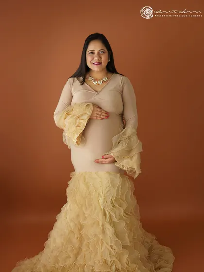 A beautiful solo portrait in a ruffled champagne gown. The warm, earthy backdrop complements the dress perfectly, creating a sophisticated and elegant look.