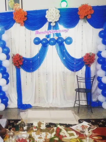 This is a budget-friendly naming ceremony decoration using blue and white drapes and balloon pillars. It provides a simple yet elegant backdrop for the function.