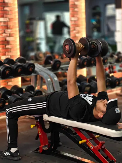 A client performs a flat dumbbell press, a fundamental movement for building a powerful chest. We emphasize a full range of motion for optimal results.