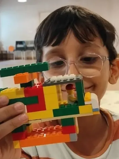 A student proudly displays the helicopter he built, a project that combines creative design with mechanical principles.