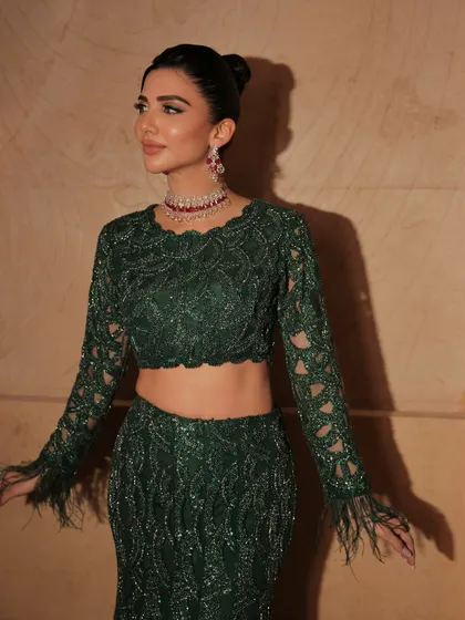 The feather details on the sleeves add a touch of drama to this elegant look. The makeup is kept clean to balance the outfit.