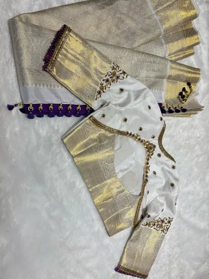 White silk blouse with gold and purple embroidery, paired with a white and gold saree.