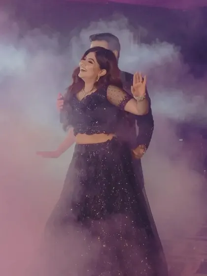 A romantic dance moment for the couple, enveloped in purple-hued smoke for a dreamy effect.
