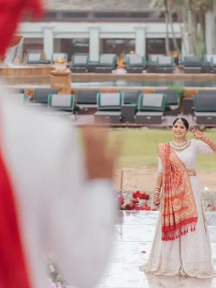 The bride's happy wave to her groom during their first look. This over-the-shoulder shot captures her excitement and the beautiful poolside setting of their destination wedding.