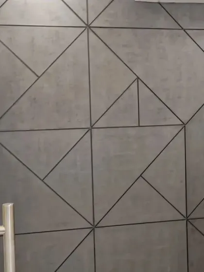 A concrete-textured wall with a geometric pattern created by dark grout lines, blending industrial texture with sharp, modern design.