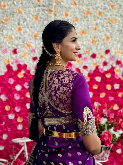 A back view of a rich purple blouse with heavy gold floral embroidery covering the entire back panel. The unique sleeve design adds another layer of custom detail to this bridal look.