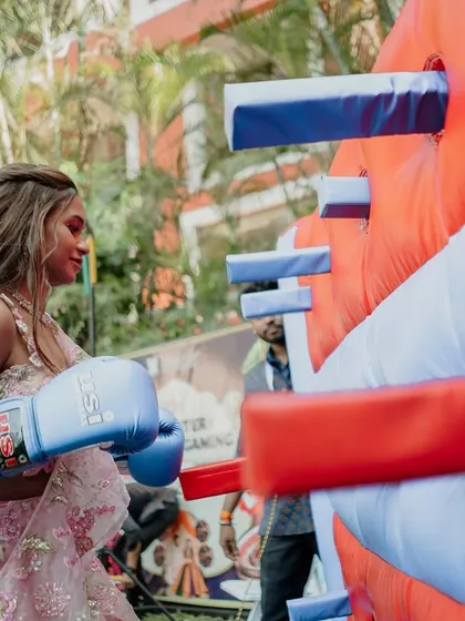 Carefree joy amidst the carnival bustle. The bride herself joins in the fun, taking a swing at the boxing game, creating unforgettable, playful memories.